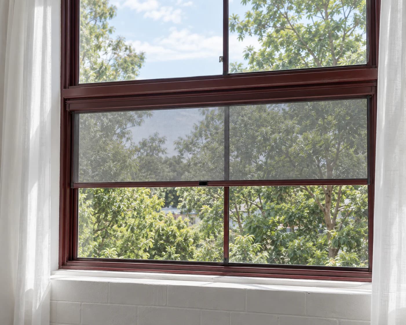 Pull-down fly screen partially lowered over a residential window