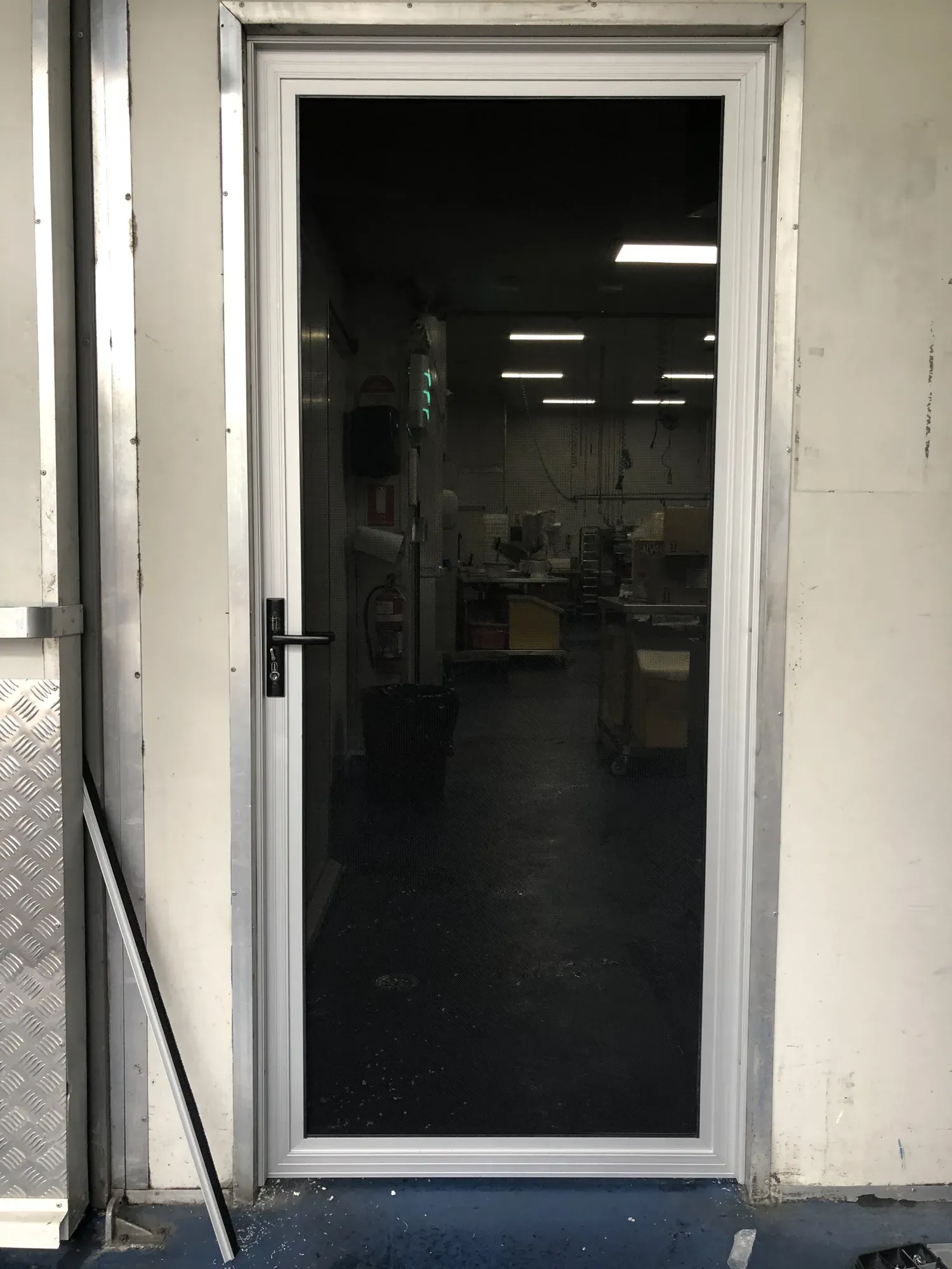 Black security screen door installed at the entrance to a commercial kitchen.