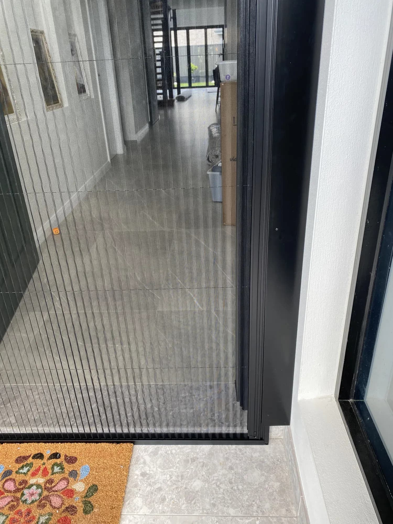 Black pleated retractable flyscreen installed beside a residential doorway.