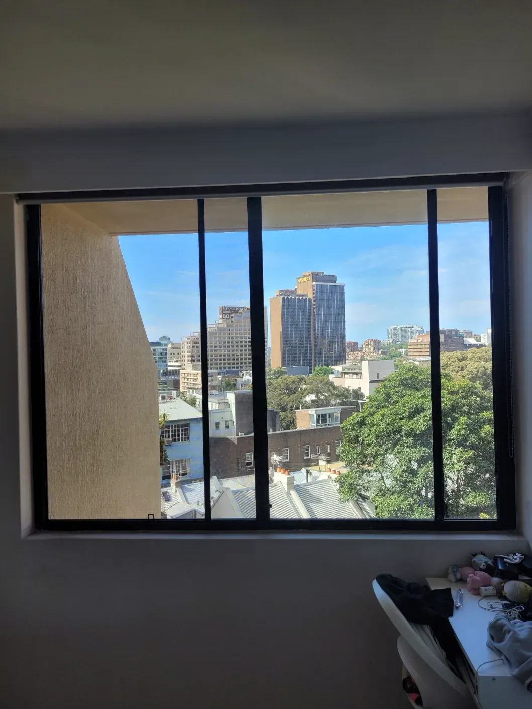 Black sliding flyscreen fitted to an apartment window viewed from inside.
