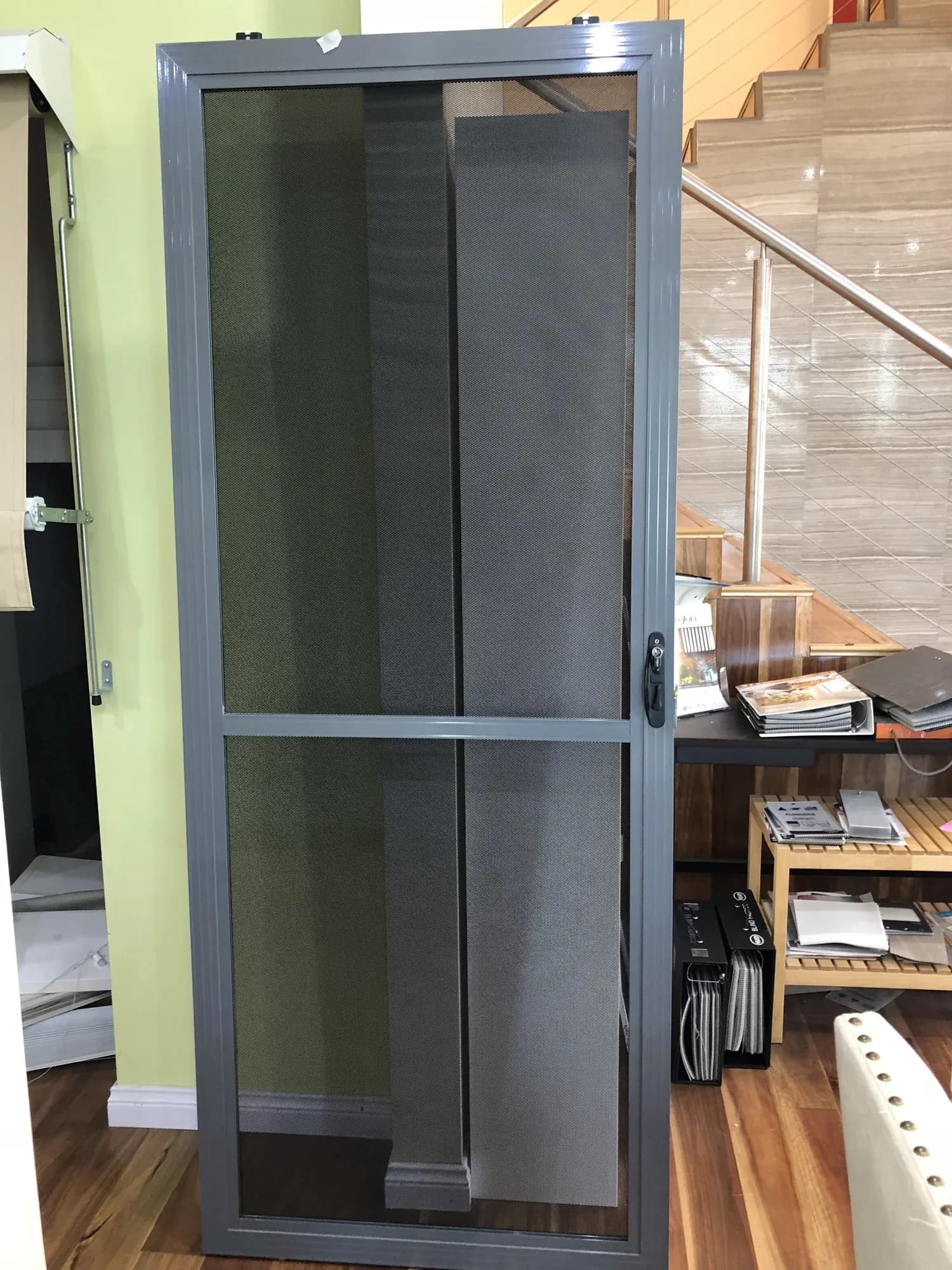 Grey hinged flyscreen door displayed indoors with a full-height mesh panel.